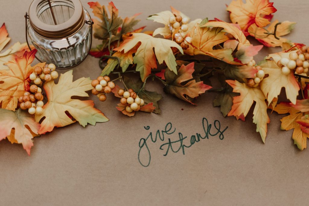 Table with fall leaves on it and "give thanks" written on brown paper.